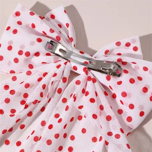 Red polka dot bow hair clip detail view, featuring sweet fabric design with secure metal spring clip.
