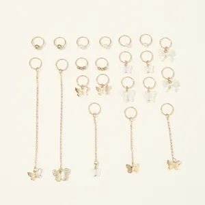 Detailed view of gold braid rings, pearl charms, and butterfly pendants for stylish hair DIY.