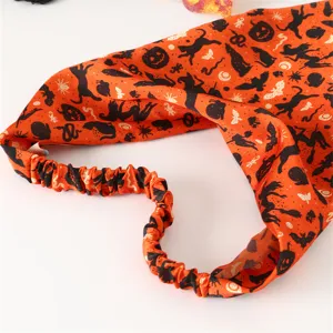 Halloween hair accessory detail showing orange fabric with spooky festive print and elastic band.