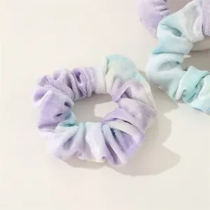Detailed close-up of velvet tie-dye hair scrunchie, soft texture and gradient purple blue color.