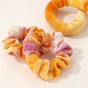 Detailed view of colorful tie-dye velvet hair scrunchies and styling tools for daily wear.