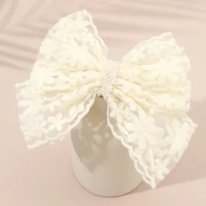 Elegant white lace bow hair clip with pearl center, perfect for stylish summer hairstyles.