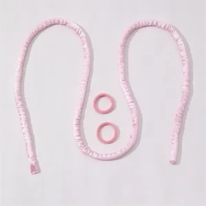 Gros plan sur l'ensemble de bigoudis sans chaleur en satin rose avec deux chouchous.