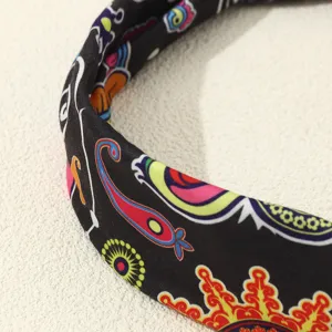 Close-up detail of a retro ethnic print fabric headband, showing colorful totem design.