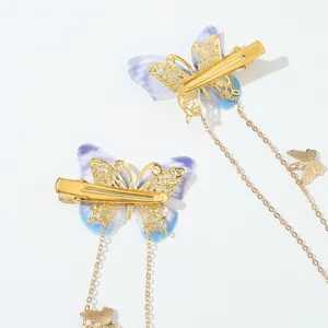 Nahaufnahme von lila Schmetterlings-Haarspangen mit goldenen Ketten und Quasten.
