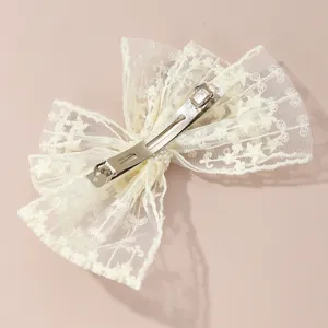 White lace bow hair clip detail shot, elegant mesh hair accessory with pearl decor.