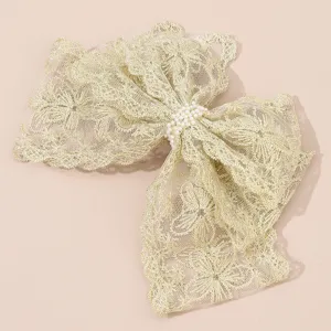 Gold lace hair bow detail shot, elegant hairpin with faux pearl center for women's hairstyles.