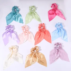 Vue détaillée des chouchous en satin coloré avec rubans courts, accessoires cheveux doux.