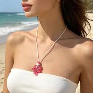 Collier pendentif fleur en résine rose avec cordon tressé blanc pour les vacances à la plage.