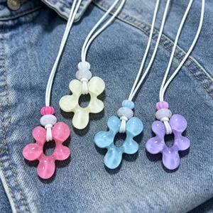 Collier pendentif fleur en résine colorée avec cordon blanc, style vacances de plage.