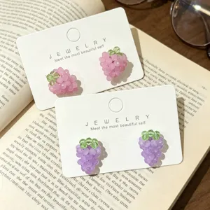 Gros plan de boucles d'oreilles clous grappes de raisin roses et violettes, bijoux.