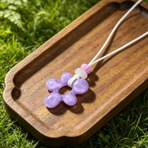 Collier pendentif fleur en résine violette avec cordon tressé blanc style plage bohème chic