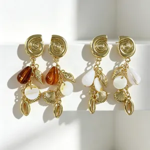 Primer plano detallado de pendientes colgantes de concha dorada con dijes muy elegantes.