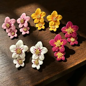 Gros plan détaillé des boucles d'oreilles doubles fleurs en émail coloré et paillettes.