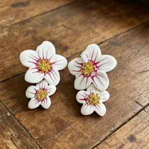 Ravissantes boucles d'oreilles asymétriques en émail blanc avec fins détails dorés.