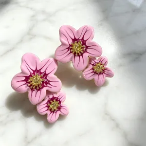 Gros plan de boucles d'oreilles fleuries en émail rose élégant avec centre doré.