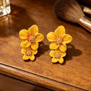 Gros plan détaillé de boucles d'oreilles de fleurs en émail coloré sur fond de table en bois.