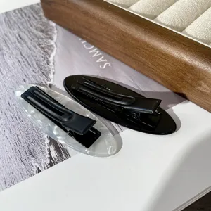 Detalle de elegantes pinzas ovaladas para el pelo, horquillas pico de pato blancas y negras de moda.