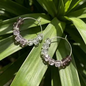 Detail van paarse en heldere kristalparel oorringen, elegante en modieuze dames sieraden.