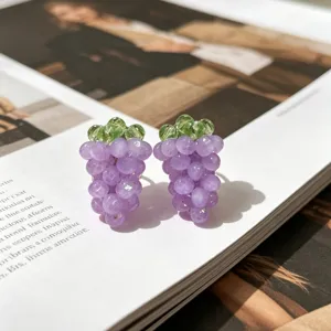Gros plan des boucles d'oreilles mignonnes raisin violet avec feuilles vertes, bijoux.