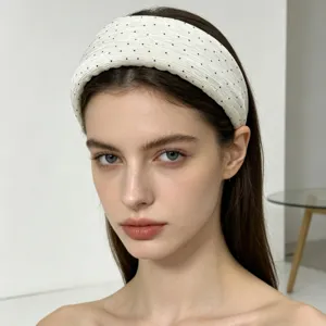 Primo piano dettagliato di un elegante cerchietto largo bianco a pois neri, tessuto plissé.