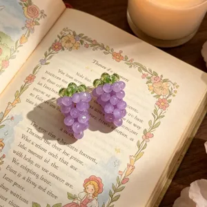 Gros plan détaillé de jolies boucles d'oreilles raisin violet sur un livre ancien.