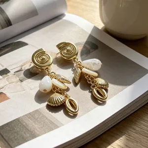 Pendientes colgantes de concha y perla dorada, detalle de joyería de estilo de vacaciones de verano.