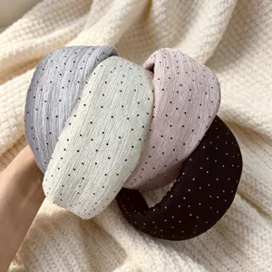 Dettaglio ravvicinato di cerchietto largo plissettato in chiffon a pois, morbida texture.