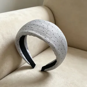 Primo piano del dettaglio del cerchietto in chiffon grigio plissettato con pois neri.