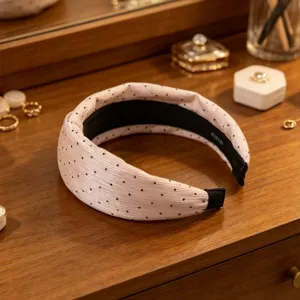 Primo piano dettagliato di un cerchietto per capelli a pois rosa in chiffon su comò in legno.