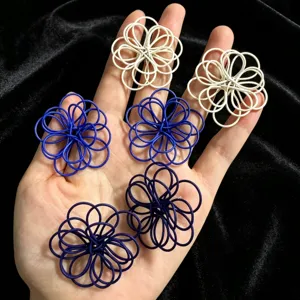 Detail view of handmade woven hollow flower earrings in white and blue shades, chic design.