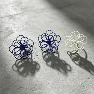 Close-up of handmade hollow wire flower earrings in blue and white, showcasing intricate petal design.