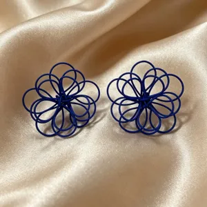 Close-up detail shot of elegant blue woven wire flower earrings with a unique handmade look.