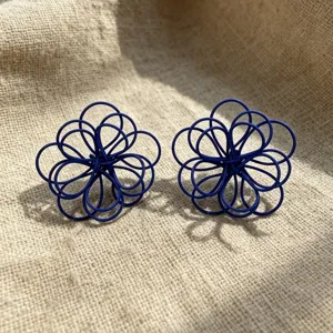 Detailed shot of dark blue woven flower earrings, handmade hollow design, elegant vacation style.