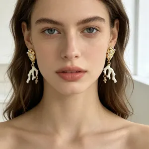 Detailopname van elegante gouden koraaltak oorbellen met sprankelende kristallen strass-steentjes.