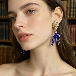 Gedetailleerde close-up van vergulde oorbellen met blauw koraal en schitterende strass-steentjes.