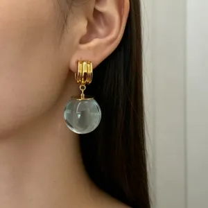 Vue en gros plan détaillée des élégantes boucles d'oreilles créoles dorées avec cristal.