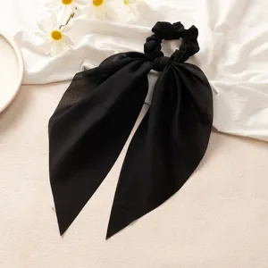 Gros plan sur l'élastique à cheveux noir élégant avec de longs rubans en tissu doux.