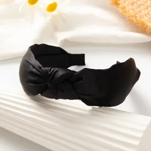 Black satin knotted headband detail shot showing smooth texture and wide brim design.