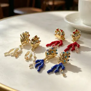 Gedetailleerd overzicht van prachtige schelp koraal oorbellen met kleurrijk emaille en strass.