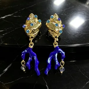 Gouden schelp en blauwe koraal oorbellen met sprankelende strass steentjes en emaille details.