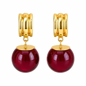 Boucles d'oreilles créoles dorées de style français avec sphères de cristal rouge foncé.