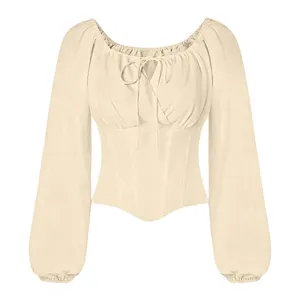 Detailweergave van de beige blouse met lange mouwen, veters en een strak korsetlijfje.