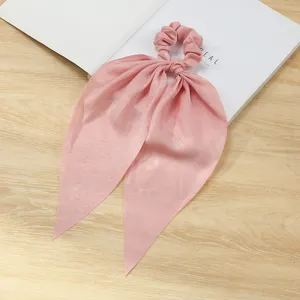 Vista dettagliata dell'elastico per capelli rosa con tessuto morbido e design con fiocco lungo.