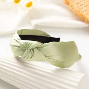 Light green satin knotted headband detail shot, wide brim solid color hair accessory for women.