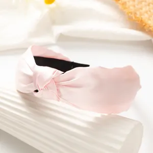Pink knotted wide hair hoop detail showing smooth satin texture and elegant design style.