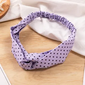 Dettaglio fascia per capelli in tessuto floreale viola, cerchietto elastico con stelle.