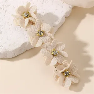 Vue détaillée de la pince à cheveux fleur en tissu champagne avec des strass étincelants.