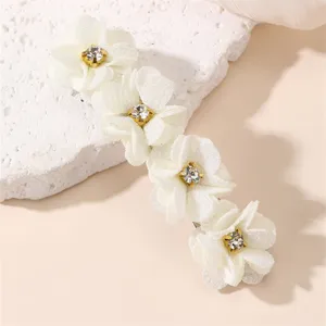 Gros plan de la pince à cheveux fleur en tissu blanc avec strass étincelant, accessoire chic.