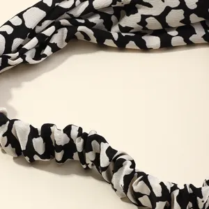 Close-up detail of smooth black and white patterned hair band fabric, showing soft silky texture.